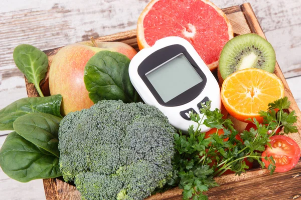 Glucose meter for measuring sugar level and ripe natural fruits and vegetables. Concept of diabetes, healthy lifestyles and nutrition