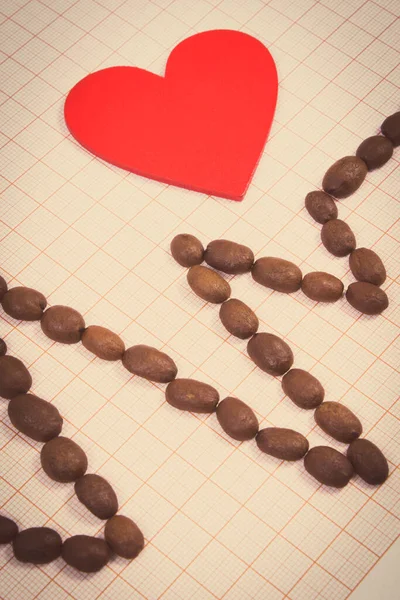 茶色のローストコーヒー粒とグラフ紙の赤いハートの心電図ライン Ecgハートリズム 医学と医療の概念 — ストック写真