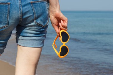 Kalp şeklinde güneş gözlüklü bir kadın eli. Yaz ve tatil zamanı