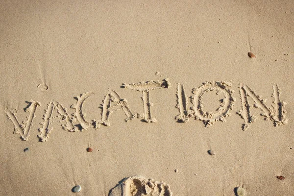 Inscription vacation on sand at beach. Concept of summer time