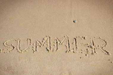 Yazın kumsalda kumlara yazılmış. Tatil zamanı kavramı