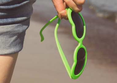 Kalp şeklinde güneş gözlüklü bir kadın eli. Yaz ve tatil zamanı. Vintage fotoğraf