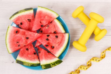 Taze karpuz, fitness ve santimetre için dambıl, sağlıklı beslenme kavramı, inceltme ve meyve içeren doğal mineraller ve vitaminler.