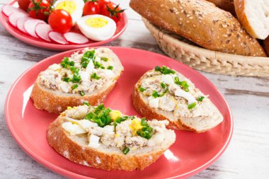 Ev yapımı uskumru ya da ton balığı ezmesi, yumurta, domates, turp ve sepette taze ekmek dilimleri.