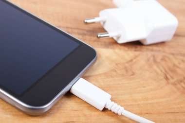 Şarj prizi bağlı cep telefonu, masada akıllı telefon şarjı