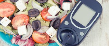 Glukometre ve taze Yunan salatası, yanında da peynir ve sebze. Şeker hastaları, diyet ve zayıflama için en sağlıklı yiyecekler.