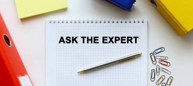 Üzerinde yazı, hesap makinesi ve kalem olan bir defter beyaz bir masanın üzerinde duruyor.