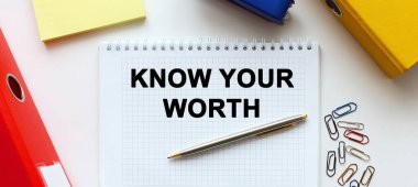 Beyaz bir arkaplanda, belge klasörünün ve ofis malzemelerinin yanında yazılı not defteri. İş konsepti.