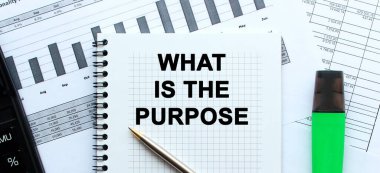 Ofis masasındaki mali tabloların üzerinde duran not defterinin sayfasına 