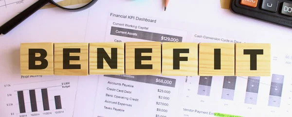 Wooden cubes with letters on the table in the office. Text BENEFIT. Financial concept.