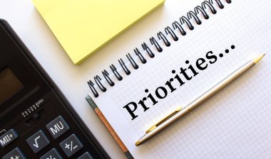 Not defterinin yanında hesap makinesi ve sarı not kağıtları yer almaktadır. İş konsepti.