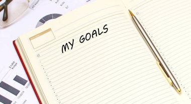 İçinde metin olan açık bir günlük, mali tabloların olduğu bir ofis masasında duruyor. İş konsepti.