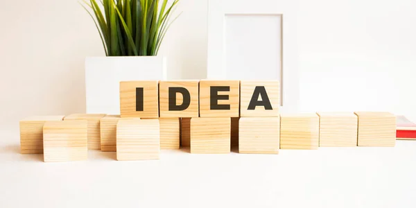 Wooden cubes with letters on a white table. White background with photo frame and house plant. — Stock Photo, Image