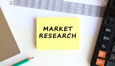 Laptopun yanındaki sarı yapışkan notlardaki yazı ve beyaz ofis masasındaki hesap makinesi. İş konsepti.