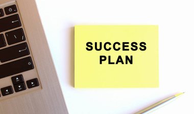 Beyaz ofis masasındaki laptopun yanındaki sarı yapışkan notlardaki yazı. İş konsepti.