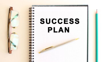 Beyaz arka planda yazılı not defteri, kalem ve gözlüğün yanında. İş konsepti.