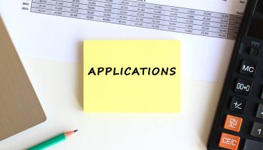 Laptopun yanındaki sarı yapışkan notlardaki yazı ve beyaz ofis masasındaki hesap makinesi. İş konsepti.