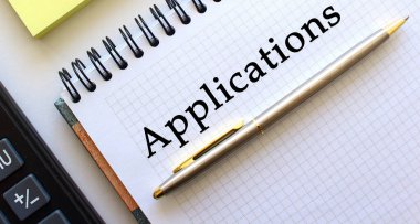 APPLICATIONS metin notları, onun yanında bir hesap makinesi ve sarı not kağıtları yatar. İş konsepti.