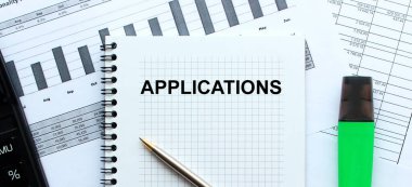 Ofis masasındaki mali tabloların üzerinde duran not defterinin sayfasına AÇIKLAR 'ı yaz. Hesap makinesinin ve işaretleyicinin yanında. İş konsepti.