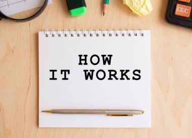 Hesap makinesi ve ofis malzemelerinin yanında, ahşap bir masada nasıl çalıştığını not al. İş konsepti.