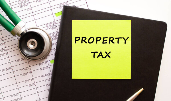 Черный кожаный блокнот с цветной наклейкой с надписью. Рядом находится фонендоскоп. Крупный план.