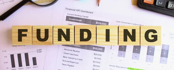 Wooden cubes with letters on the table in the office. Text FUNDING. Financial concept.