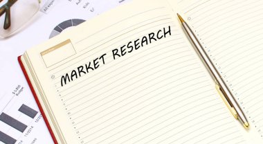 İçinde metin olan açık bir günlük, mali tabloların olduğu bir ofis masasında duruyor. İş konsepti.