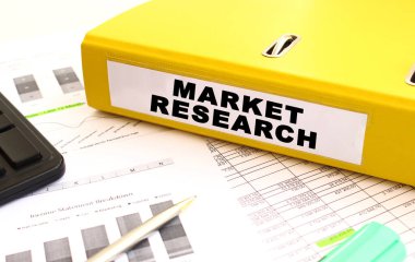 Sarı belge klasörü ofis masasının üzerinde. Bir hesap makinesine ve finans grafiklerine yakın.