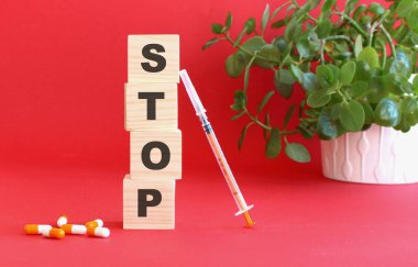 STOP kelimesi kırmızı arka planda tıbbi ilaçlı tahta küplerden yapılmıştır. Tıbbi konsept.