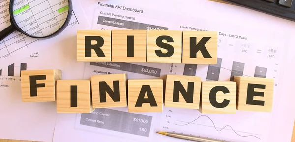 Wooden cubes with letters on the table in the office. Text RISK FINANCE. Financial concept.