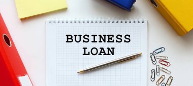 Beyaz arkaplan, belge dizini ve ofis malzemelerinin yanında metin içeren not defteri.