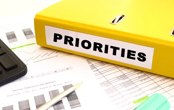 Sarı belge klasörü ofis masasının üzerinde. Bir hesap makinesine ve finans grafiklerine yakın