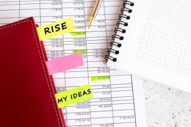 Ofis masasında üzerinde yazı olan renkli sekmelerle dolu bir iş günlüğü var..