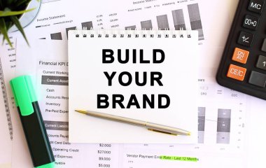 Hesap makinesi ve ofis malzemelerinin yanında beyaz arka planda markanı oluşturan bir not defteri. İş konsepti.