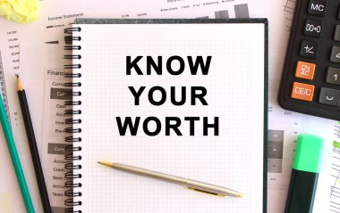 Hesap makinesi ve ofis malzemelerinin yanında, beyaz arkaplandaki değerini bilen metin notları.