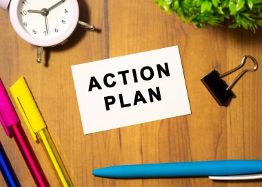 Çalışma planının yazılı olduğu bir kartvizit ofis malzemelerinin arasında, ahşap bir ofis masasında yatıyor..