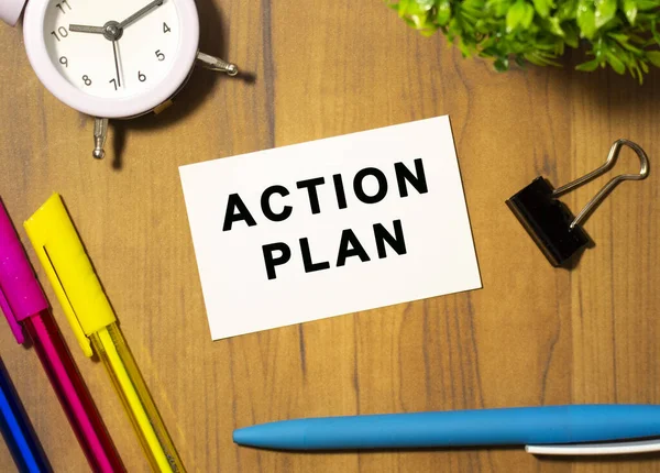 Çalışma planının yazılı olduğu bir kartvizit ofis malzemelerinin arasında, ahşap bir ofis masasında yatıyor..