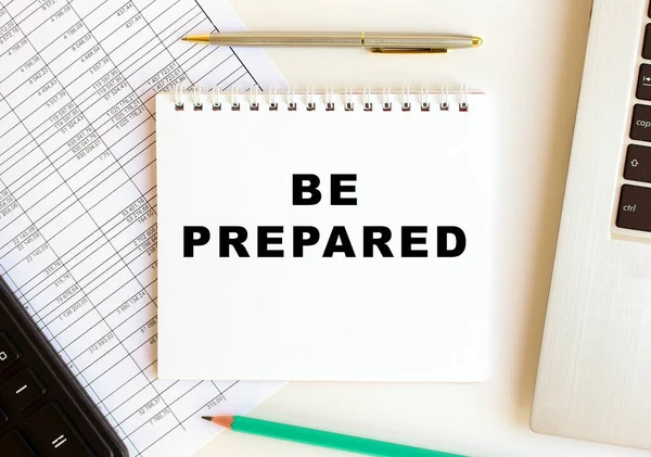 Diz üstü bilgisayar, hesap makinesi ve ofis malzemelerinin yanında beyaz bir arkaplan üzerinde hazır olun metni olan not defteri.