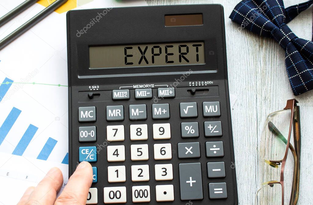 A calculator labeled EXPERT lies on financial documents in the office.