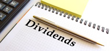 Hesap makinesi ve sarı not kağıtlarının yanında, beyaz bir arkaplan üzerinde SMS DIVIDENDS ile not.