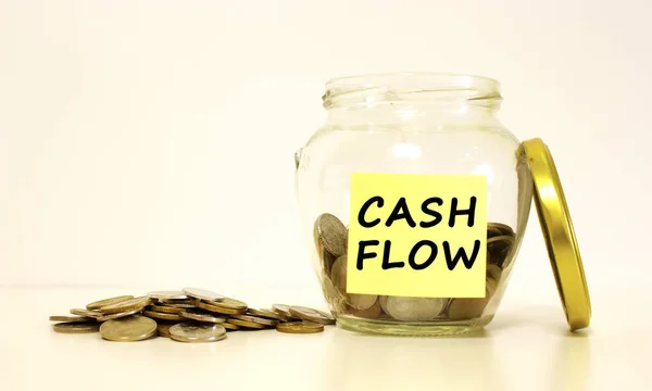 Biriktirmek için bozuk paralarla dolu cam kavanoz. Not kağıdındaki yazı CASH FLOW.