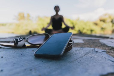 Doğadaki dijital detoks kavramı bir kadının sanatsal olarak bulanıklaşması ve cep telefonunun yakın plan görüntüsü.