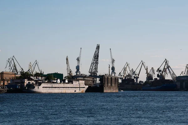 A huge white ship with tourists who travel. Port in St. Petersburg in the sea bay, loading and unloading cargo by crane