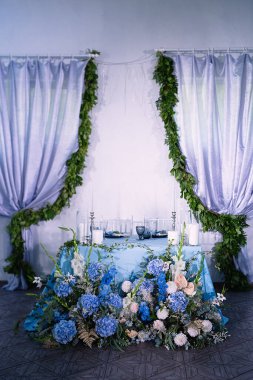 Mavi kemer ve taze çiçeklerle süslenmiş yeni evliler için bir masa..