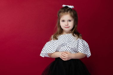 Kırmızı arka planda bir kız öğrencinin portresi, tam gelişim gösteriyor ve ileriye bakıyor.