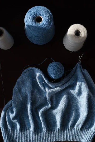 青い色の編んだ布がテーブルの上にあり隣にはウールの糸があります — ストック写真