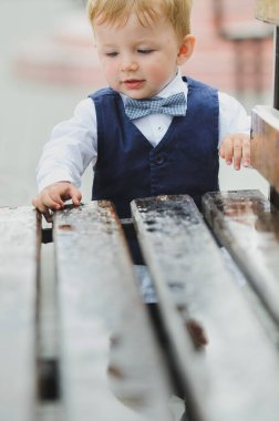 Küçük çocuk bir banka dokunur, ahşap bir bankta yağmurdan sonra bir damla su