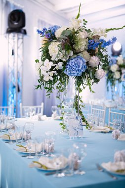 Restoranda servis edilen çok güzel masalar var. Masanın üstünde de içinde güzel taze çiçekler olan bir vazo var.,