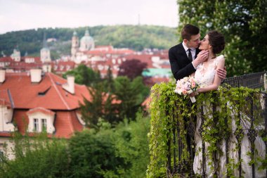 Damat ve gelin şehirde öpüşüyor, adam kıza sarılıyor, Prag 'da bir düğün.