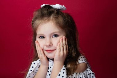 Kırmızı arka planda el ele tutuşan küçük bir kızın yakın plan portresi.